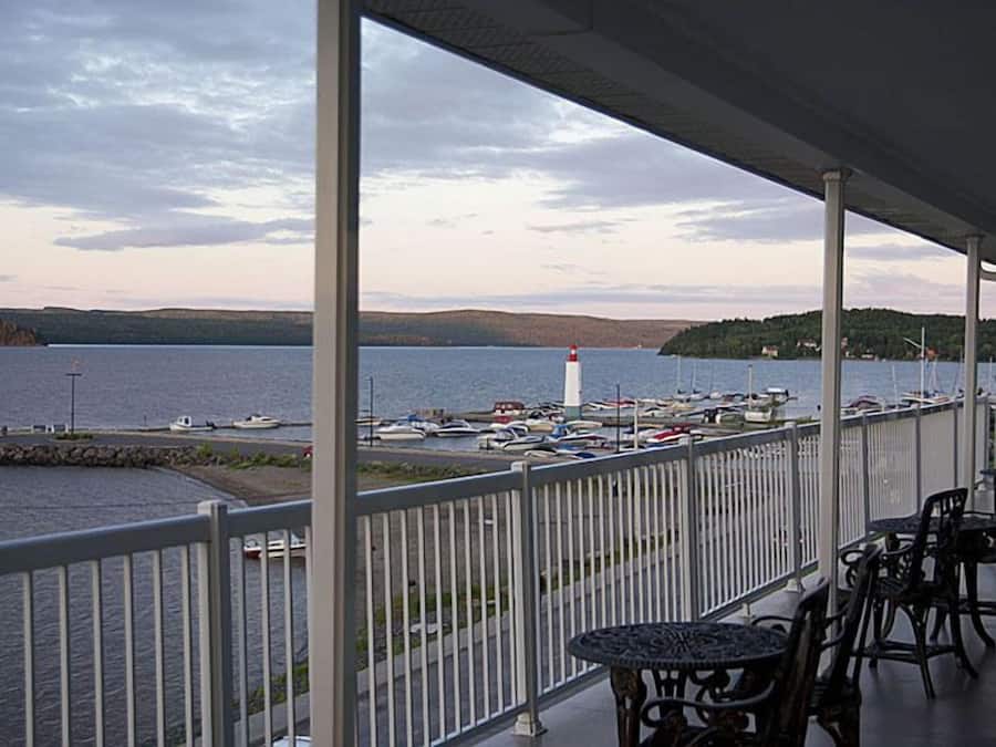 A covered outdoor area with a view of a harbor, including boats and a lighthouse.