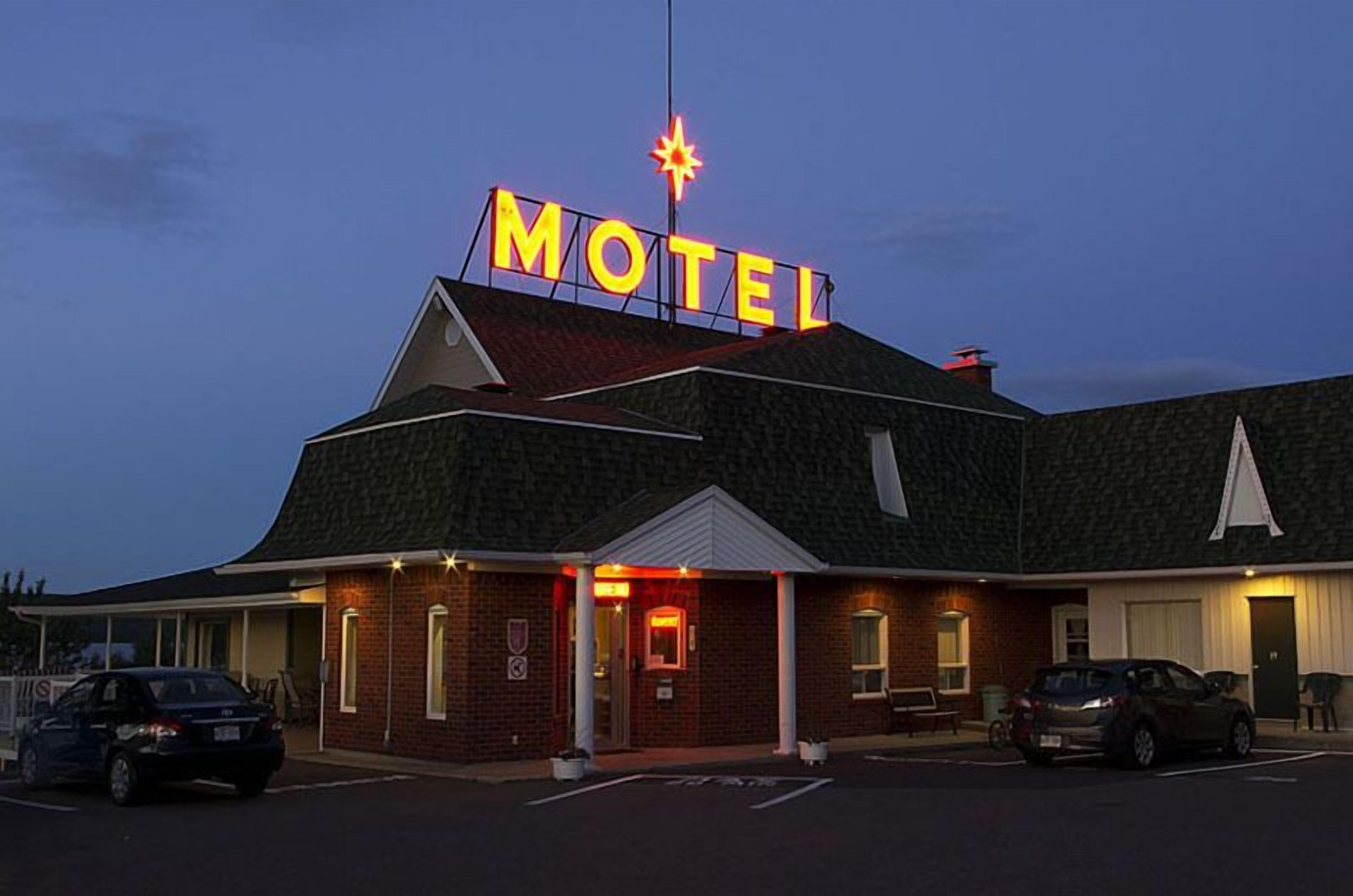 A motel with a prominent neon sign, a brick facade, and a parking lot.