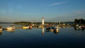 A harbor with boats docked, a lighthouse, and a calm water body. - Motel Royal (Temiscouata-sur-le-Lac)