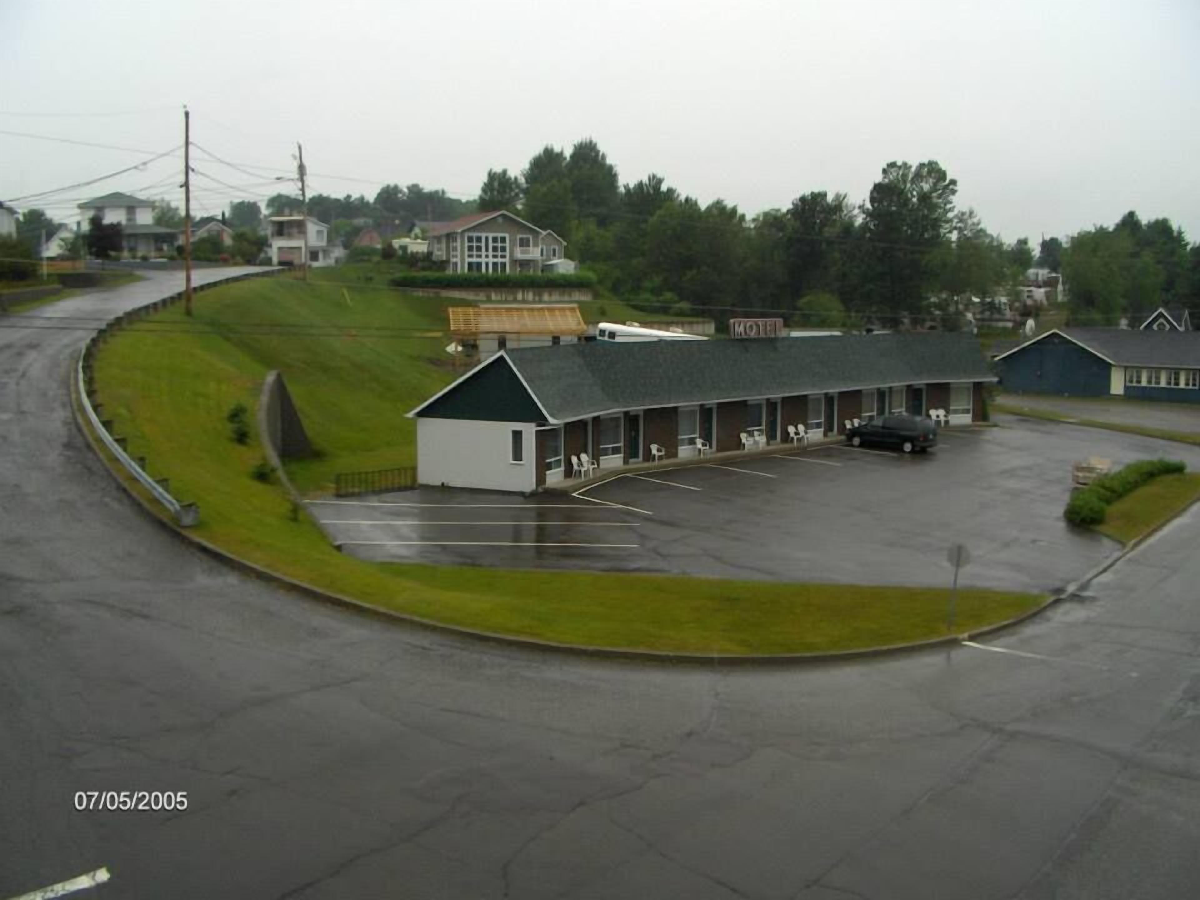 Un motel con aparcamiento, un pequeño edificio de techo verde y un letrero que dice "MOTEL".