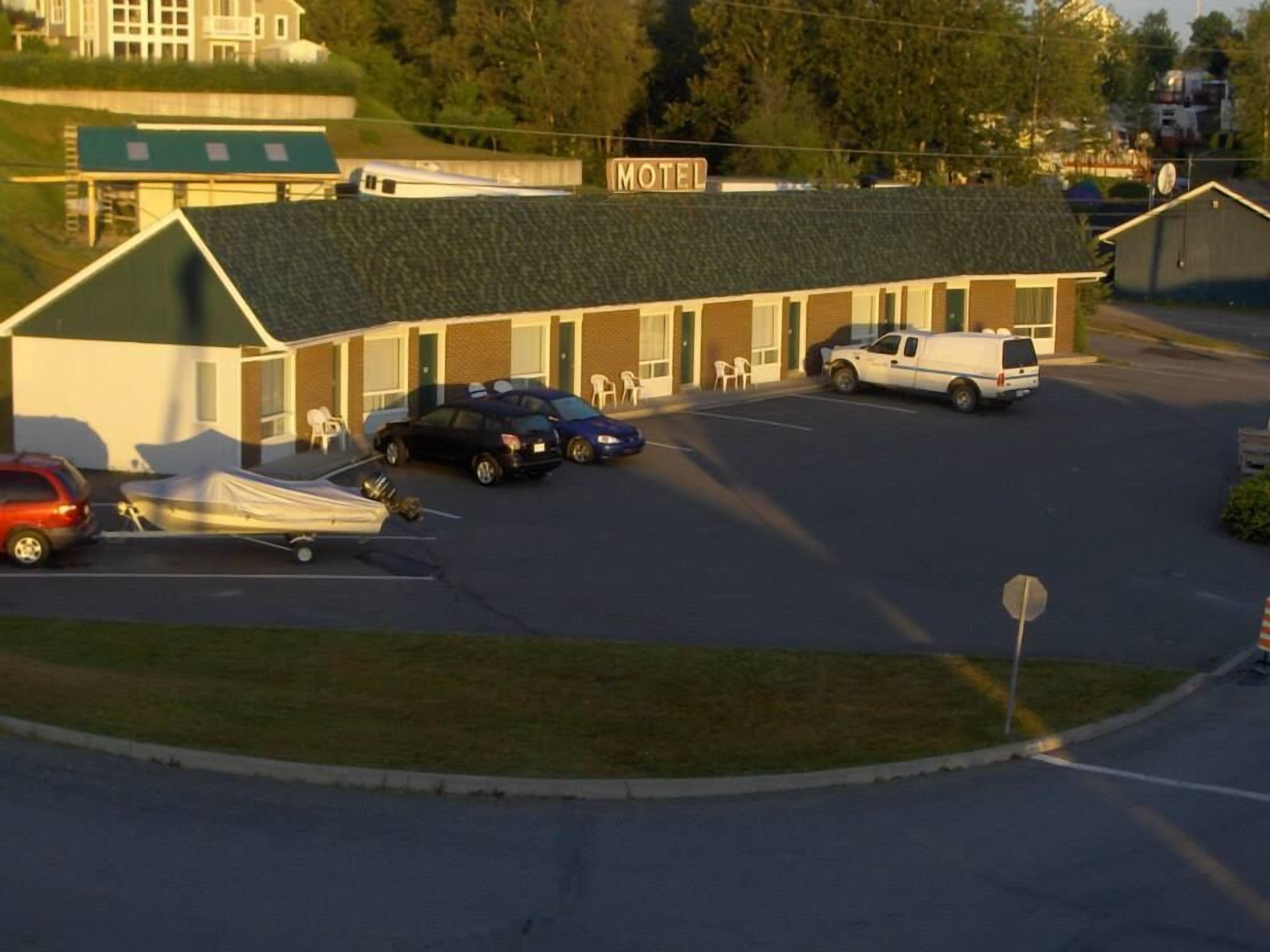 Un motel doté d’un toit végétalisé, d’un parking et d’une enseigne indiquant le nom de l’établissement.