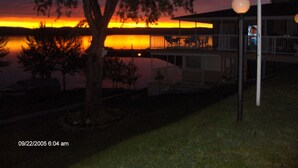 A house with a balcony overlooking a body of water during sunset. - Motel Royal (Temiscouata-sur-le-Lac)
