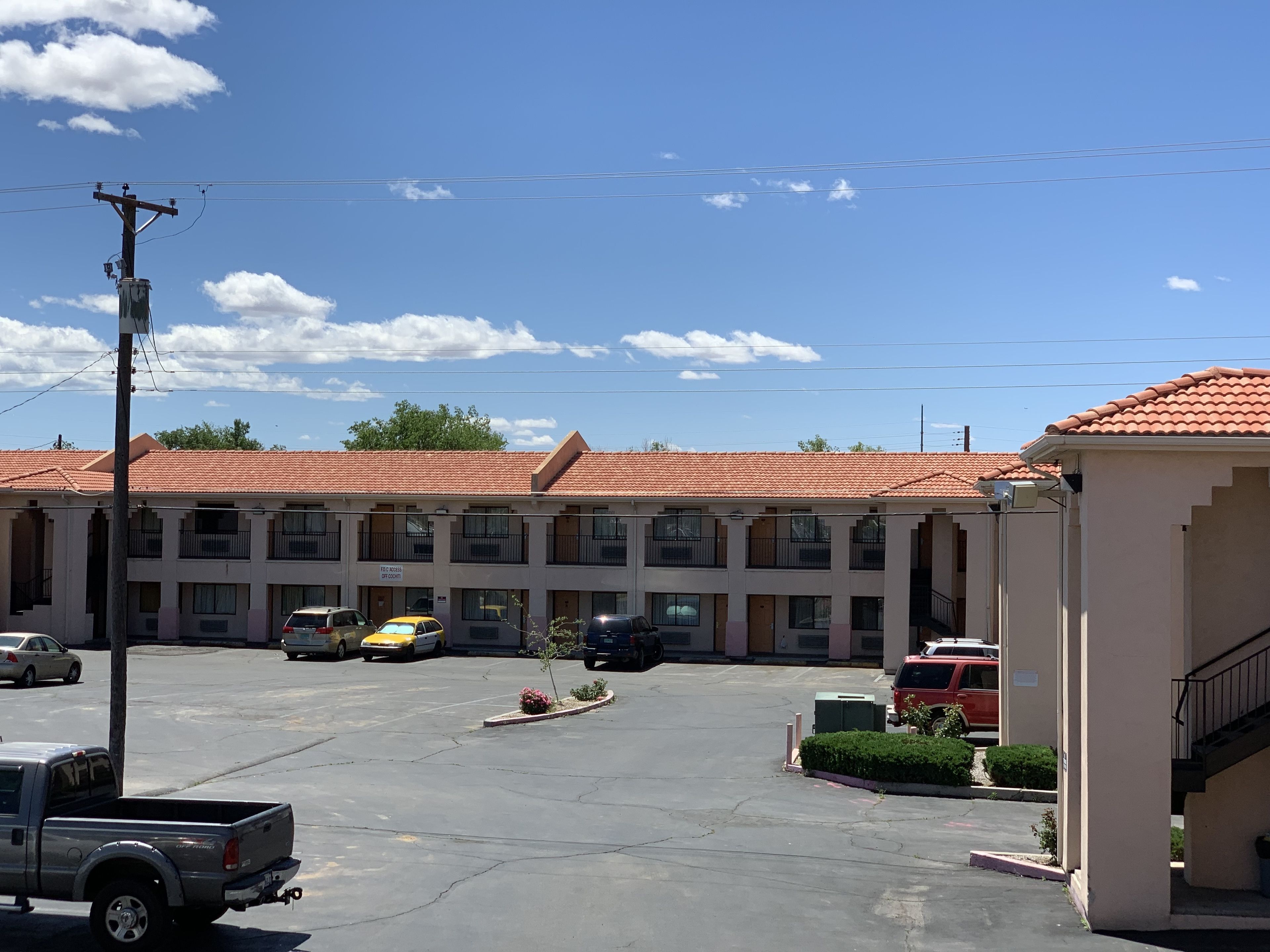 Motel de diverses plantes amb teulada vermella, aparcament i alguns vehicles aparcats.