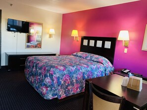 A hotel room with a bed, bedside lamps, a desk, a phone, and a TV mounted on the wall. - Luxury Inn (Albuquerque)