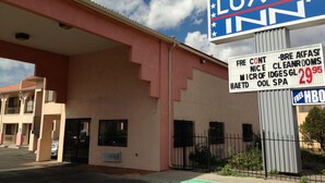 Ein Gebäude mit einem Schild für ein 'Luxury Inn', das Annehmlichkeiten wie kostenloses Frühstücksbuffet, saubere Zimmer, micro IDESGL und Spa-Dienste bietet.