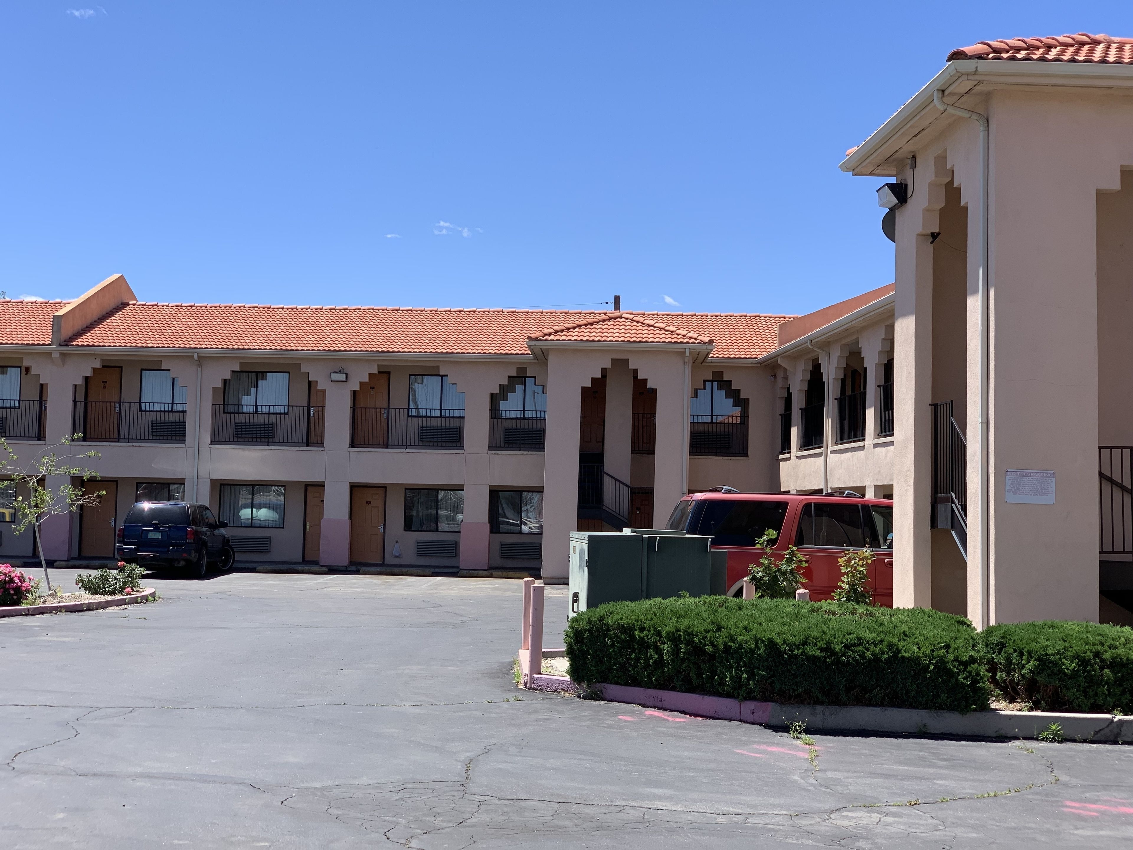 A multi-story hotel with a red-tiled roof, multiple balconies, and a parking lot.