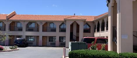 A multi-story hotel with a red-tiled roof, multiple balconies, and a parking lot.