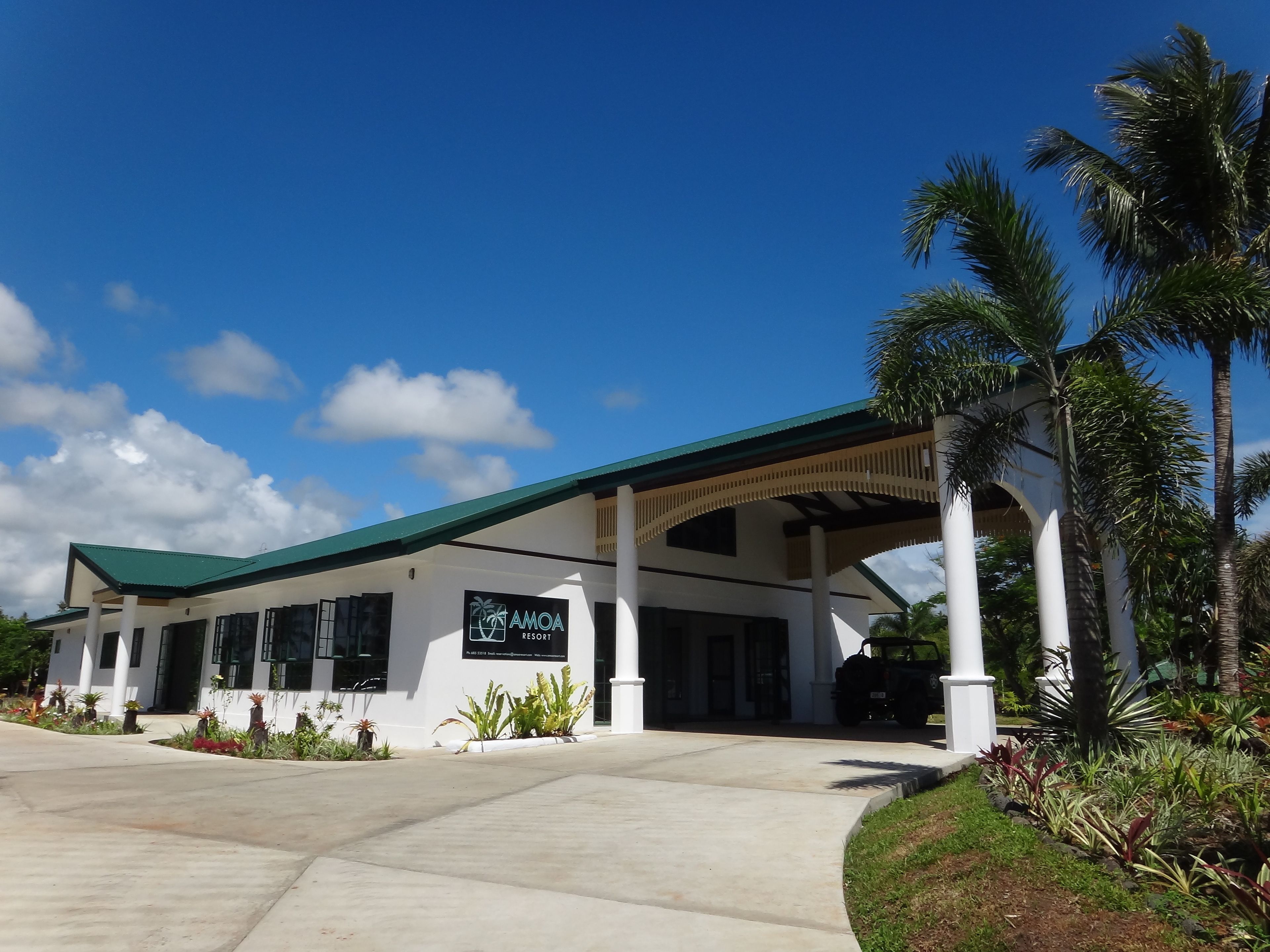A resort building with a green roof, white columns, and a sign reading "AMOA RESORT".