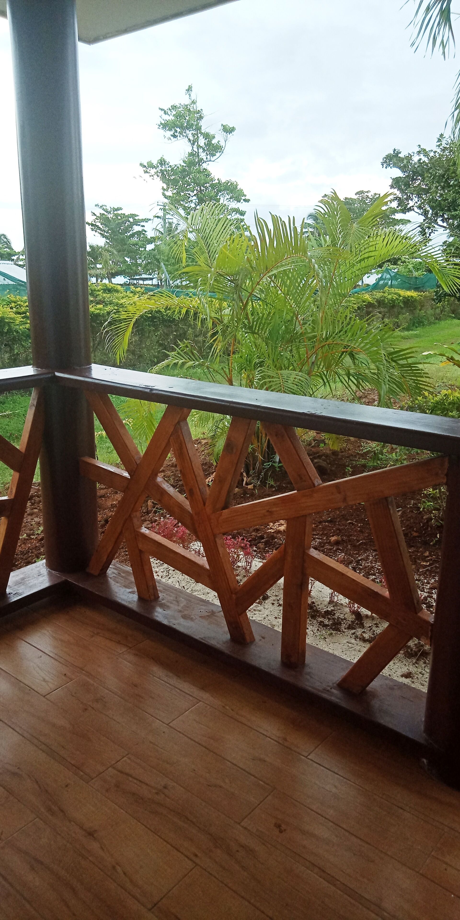 A wooden balcony with a view of a garden.