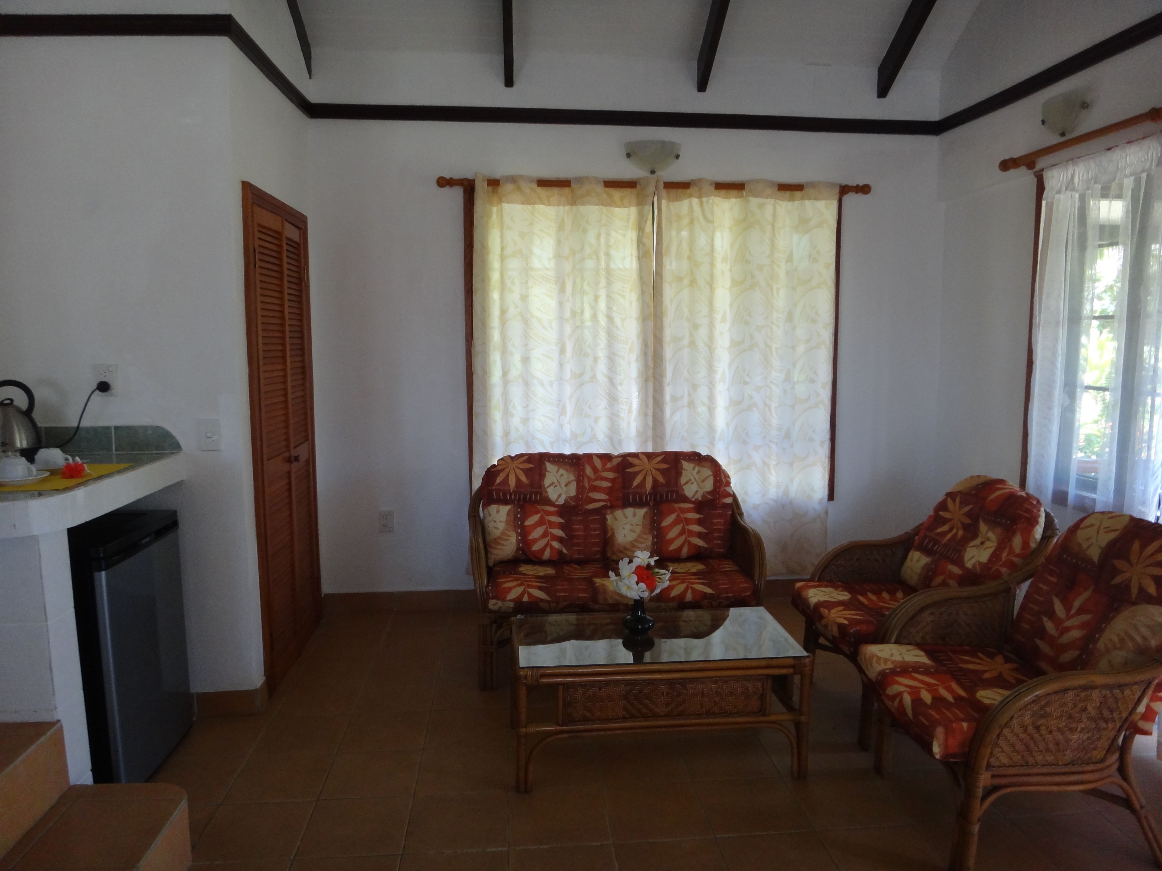 A living room with a sofa, armchairs, a coffee table, and a window with curtains.
