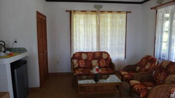 A living room with a sofa, armchairs, a coffee table, and a window with curtains.