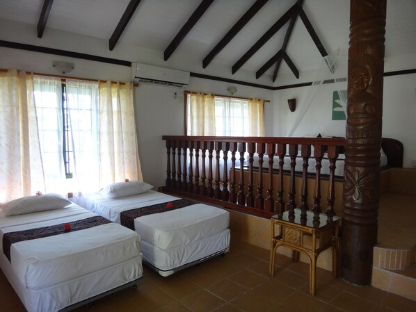 Una habitación con dos camas, una barandilla de madera y una silla.
