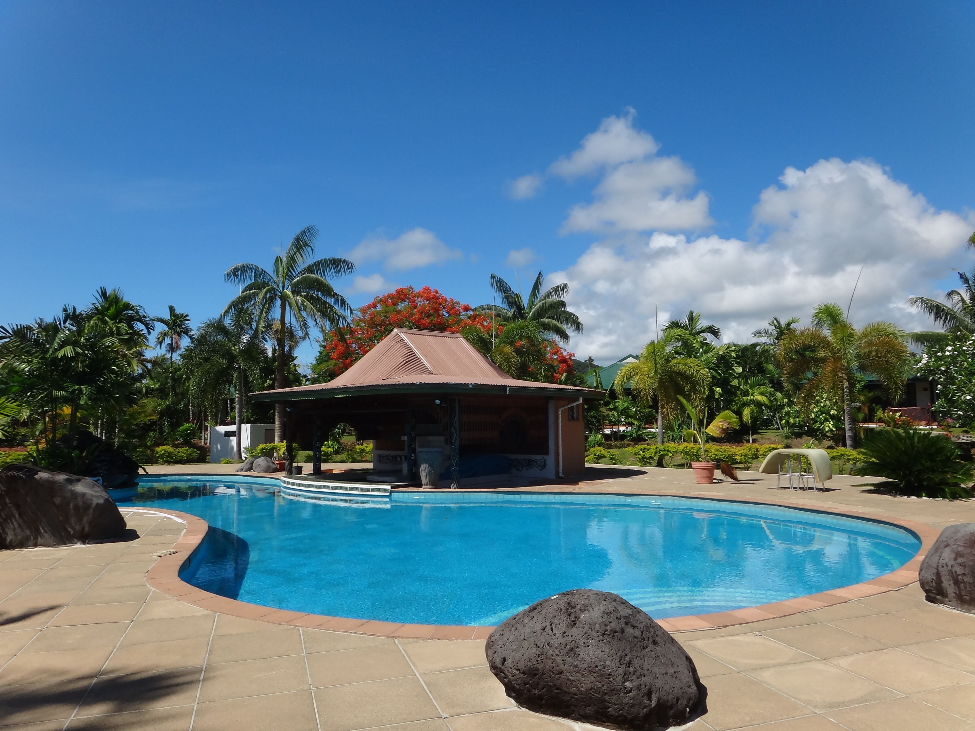 A swimming pool with a covered pavilion and tropical landscaping.