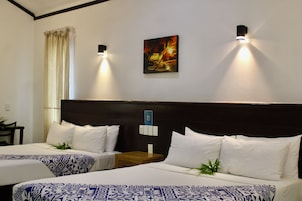 Habitación de hotel con dos camas, un cuadro en la pared y una mesita de noche con una lámpara.