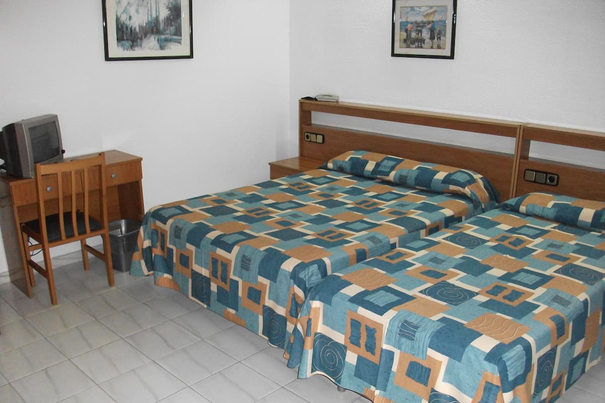 Un dormitorio con dos camas, un escritorio y una silla.