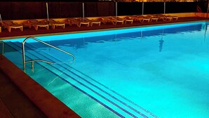 A swimming pool with clear blue water, a metal ladder, and lounge chairs along the edge. - Hotel Nautilus (Roses)