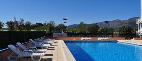 Una piscina con sillones de descanso y vistas a las montañas.