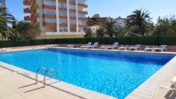 Una piscina al aire libre, sombrillas, sillones reclinables de piscina