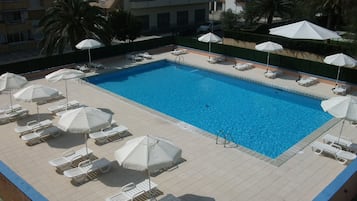 Una piscina al aire libre, sombrillas, sillones reclinables de piscina