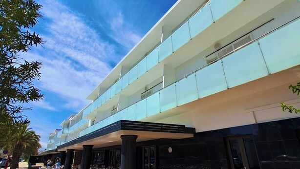 A modern hotel with a spacious outdoor seating area and a multi-story structure. - Hotel Nautilus (Roses)