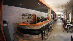 A bar area with a marble counter, stools, and a brick wall. - Hotel Nautilus (Roses)