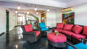 A lobby with wicker furniture, a marble floor, and a colorful abstract painting. - Safira River Front Resort (Morjim)