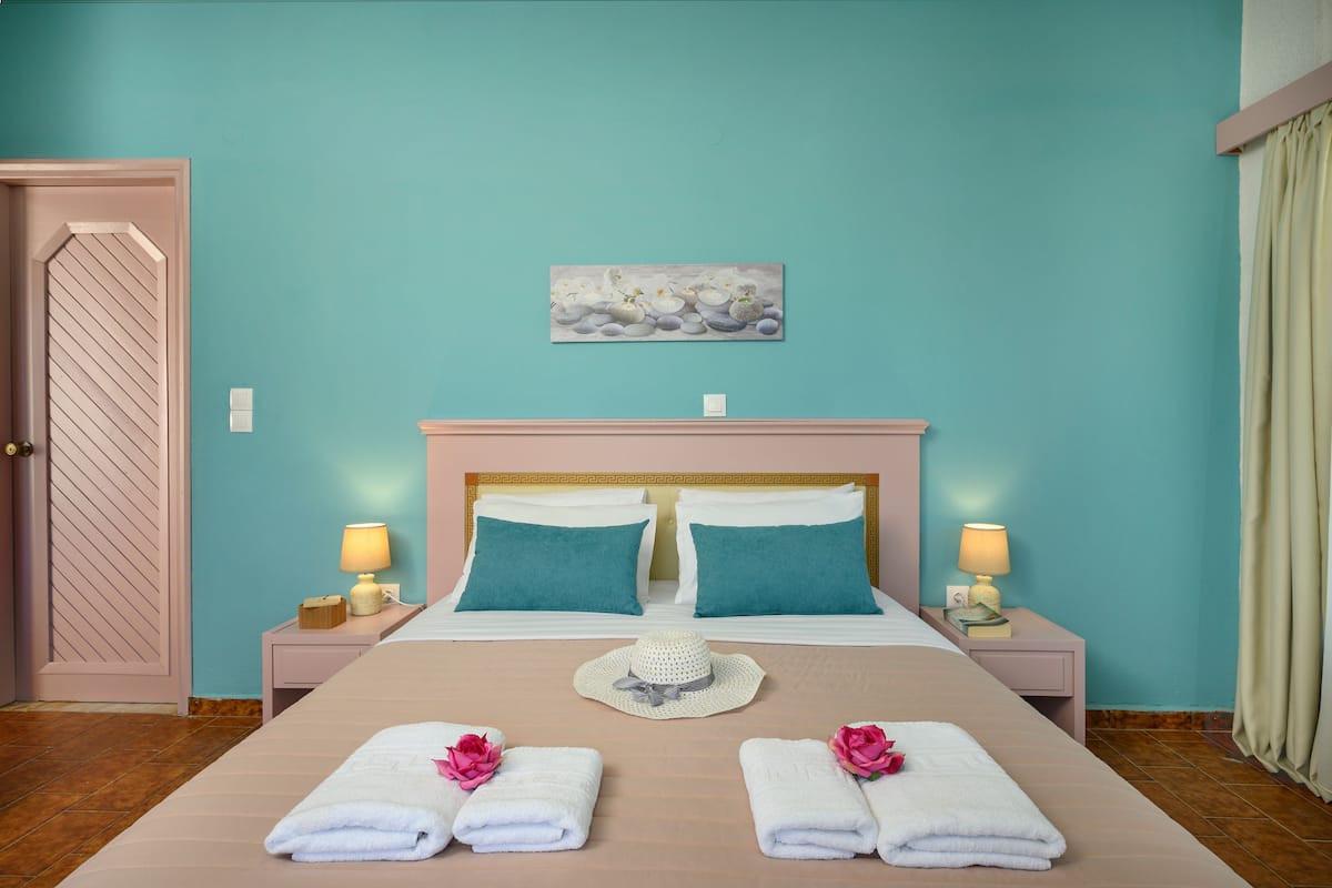 A hotel room with a bed, two bedside tables, a door, and a wall painting.