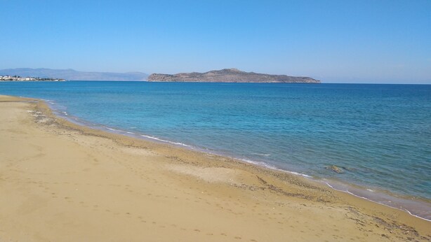 A beach with clear blue water and a distant rocky island. - Alkion Hotel (Chania)