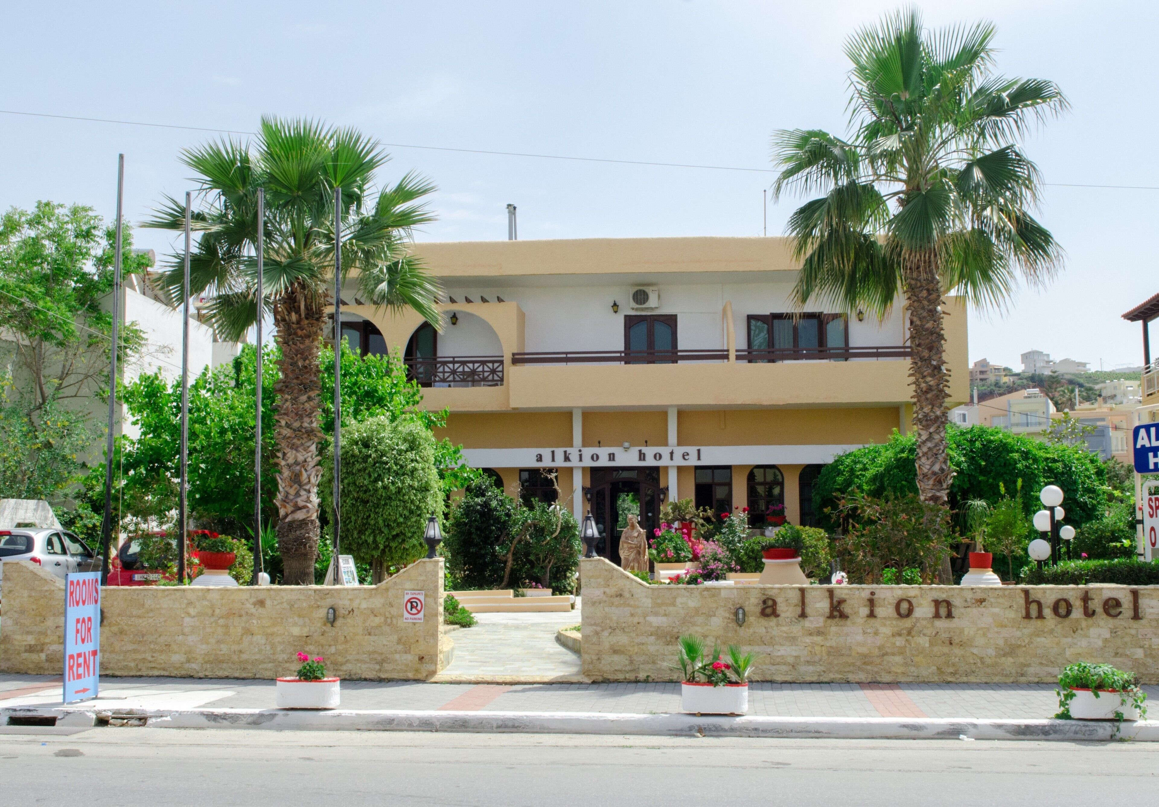 A hotel with a sign reading "alkion hotel" and a "rooms for rent" sign.