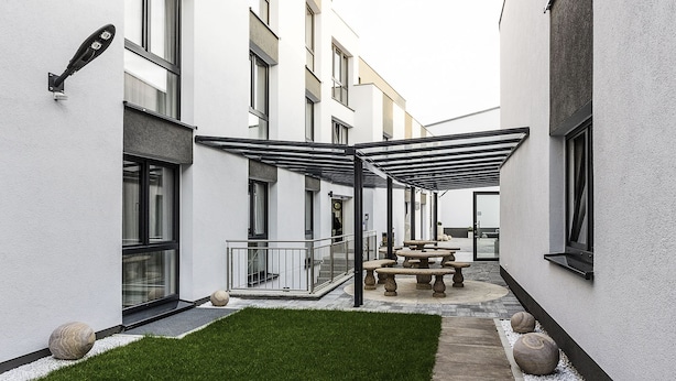 A courtyard with a covered seating area, a small lawn, and a building with multiple windows. - Naam Hotel & Apartment Frankfurt City-messe Airpor (Frankfurt)