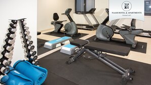 Une salle de sport équipée de matériel d’exercice, notamment des haltères, un banc et des appareils de cardio.