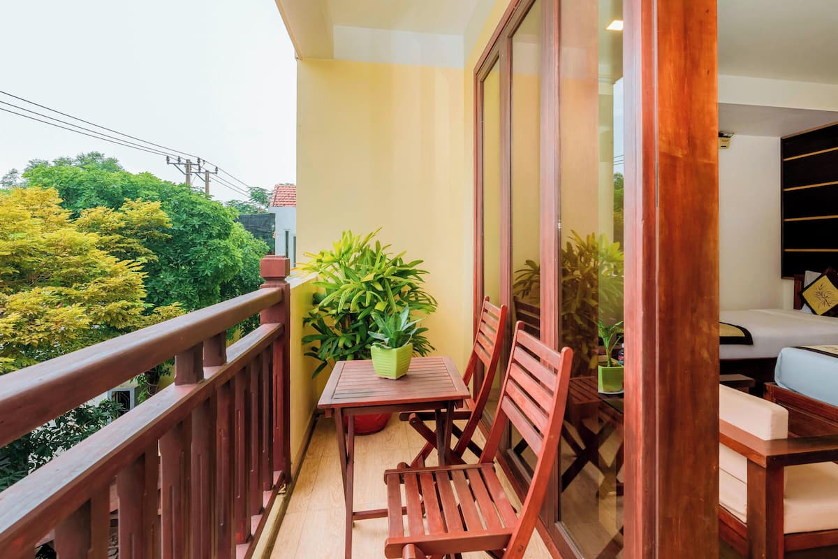 Ein Balkon mit Holzmöbeln, einem Blumentopf und Blick auf Grünflächen.