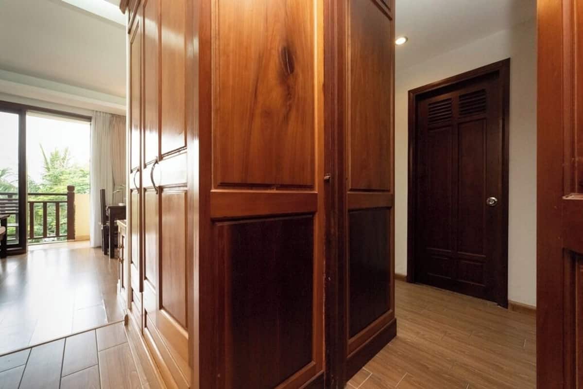 Ein geräumiger Raum mit einem Holzschrank, einer Schiebeglas-Tür zu einem Außenbereich und einer dunklen Holztür.