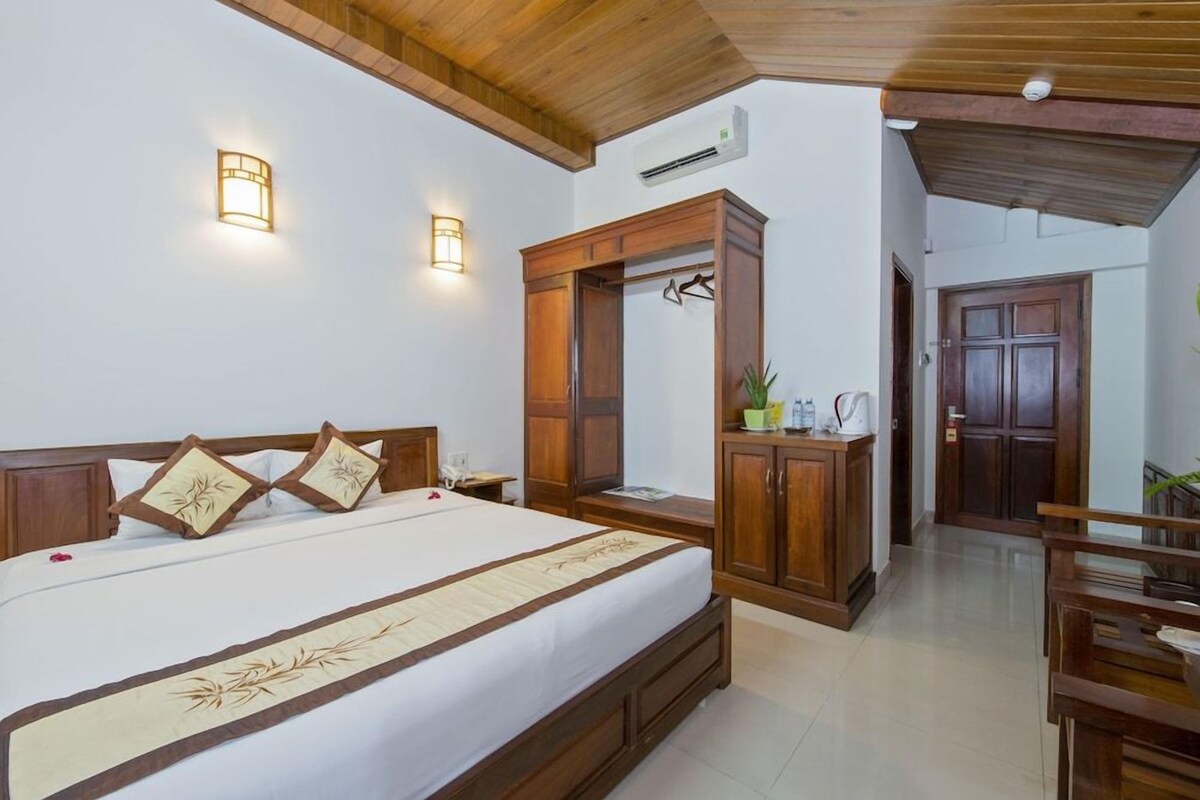 A hotel room with a wooden bed, bedside tables, a wardrobe, and a bathroom door.