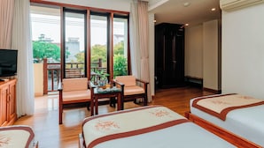 Una camera d'albergo con televisione, due letti, un tavolo da pranzo, sedie e vista all'esterno.