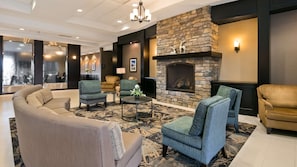 A modern lobby with a stone fireplace, comfortable seating, and a chandelier.