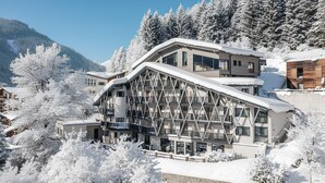 Un hôtel moderne doté d’une grande façade en verre, de nombreux balcons et offrant une vue sur une station de ski.