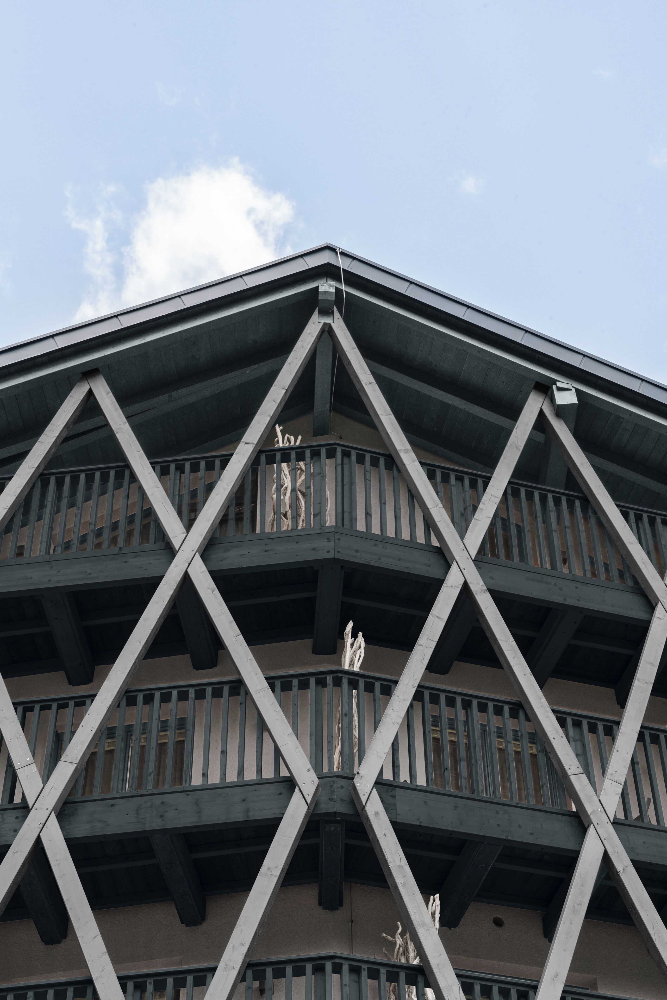 A multi-story building with a symmetrical facade, wooden balconies, and a clear sky in the background.