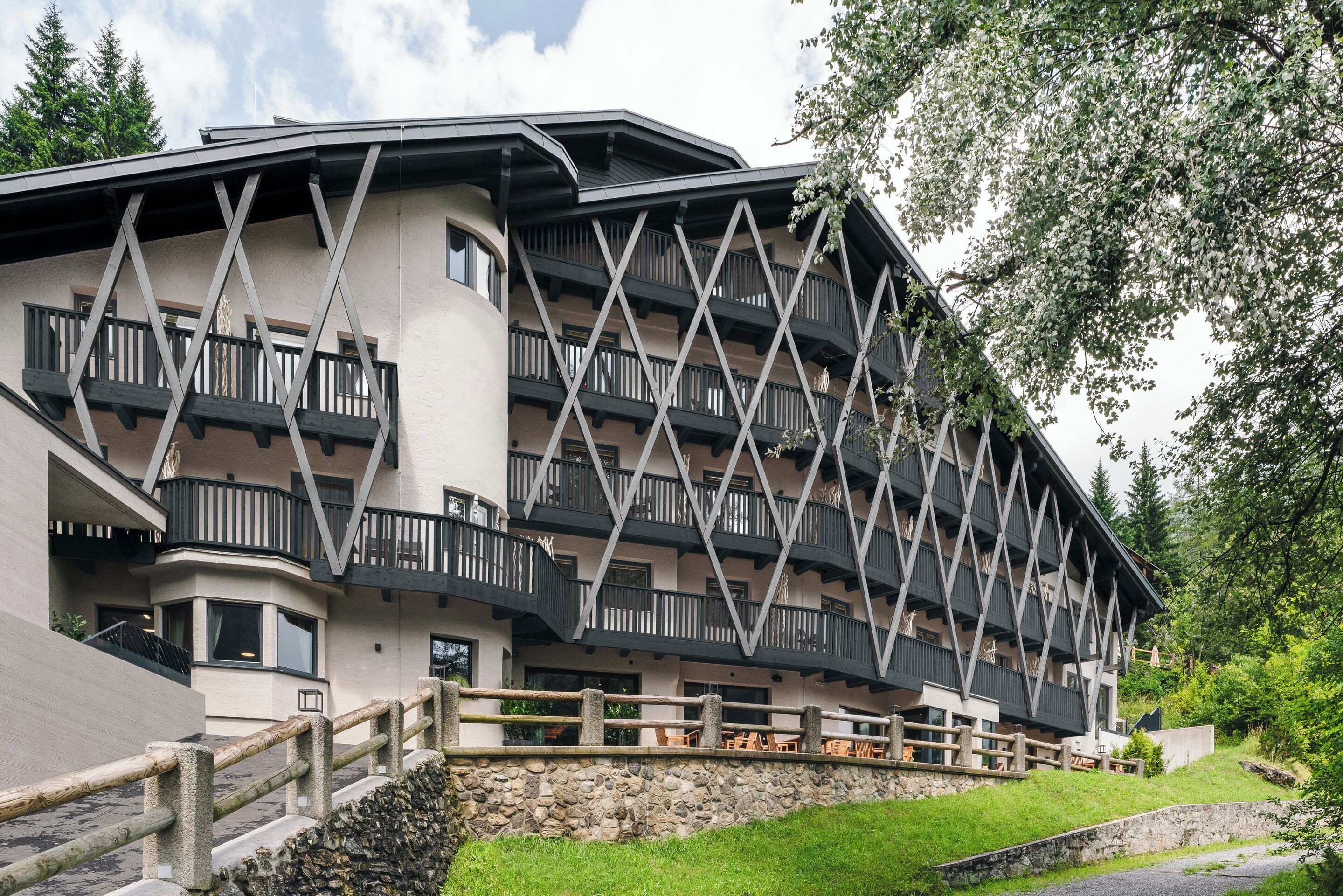 A multi-story hotel with balconies, a stone retaining wall, and outdoor seating.