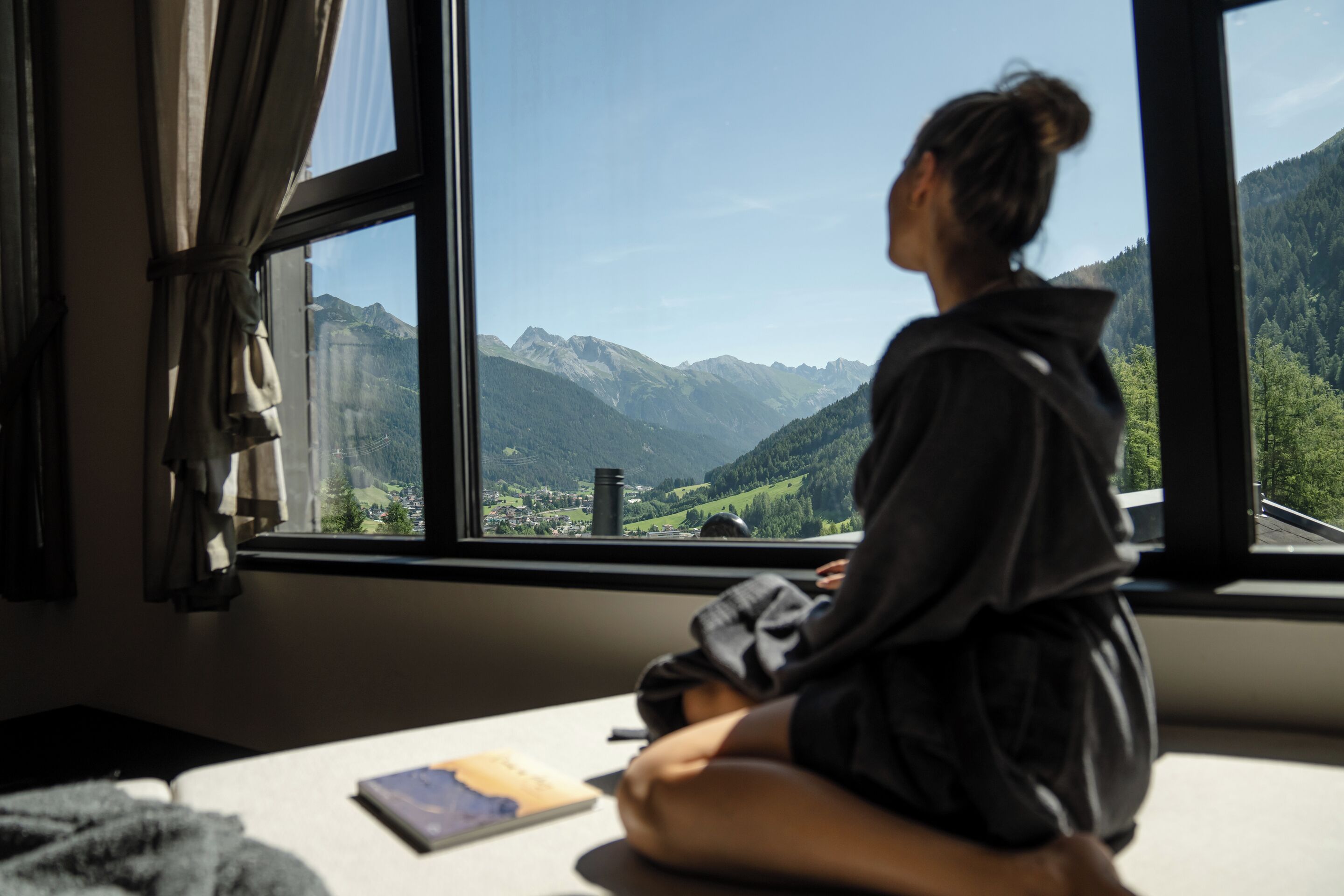 A person sitting by a window with a view of mountains.