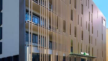Un bâtiment moderne avec des lambris en bois verticaux, de grandes fenêtres et une enseigne verte.