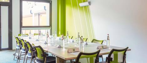 A conference room with a long table, chairs, water bottles, and a projector screen.
