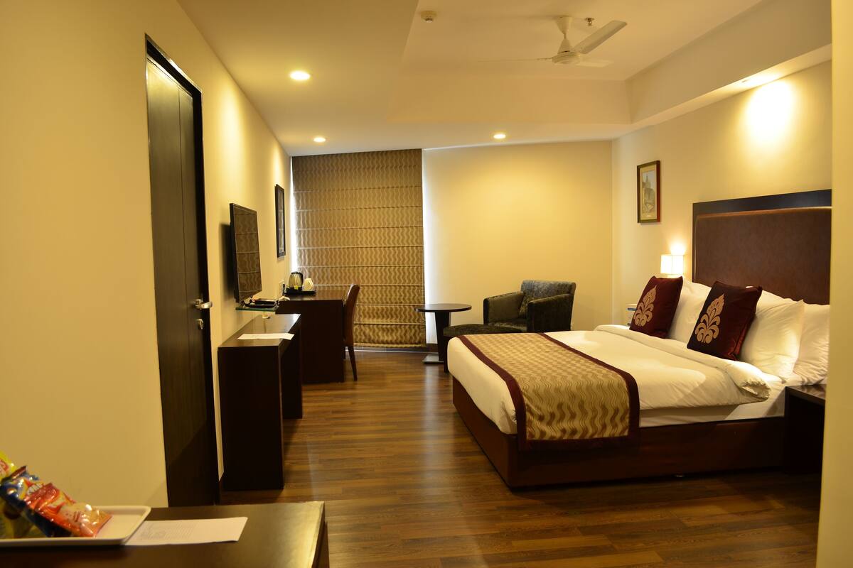 A hotel room with a bed, desk, chair, and a small table.