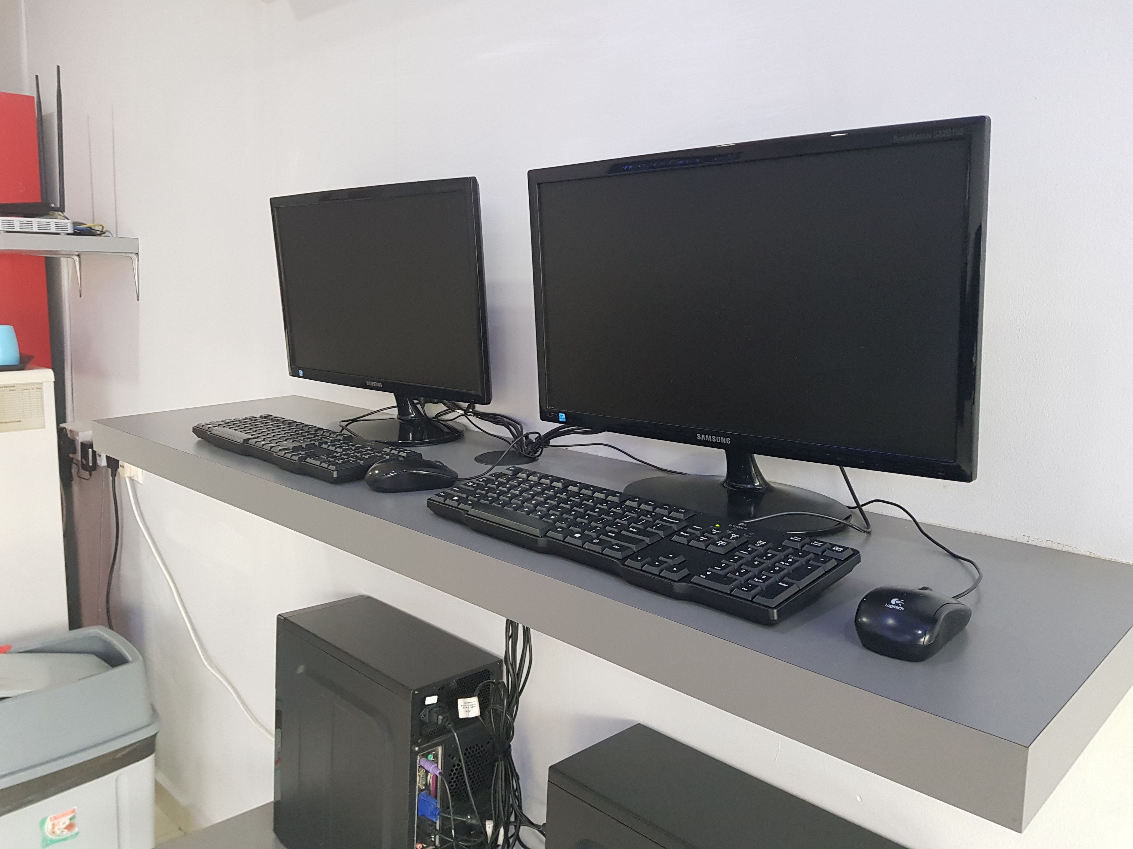 A desk with two monitors, two keyboards, and a mouse.