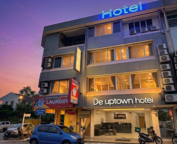 Un hôtel avec une enseigne indiquant « De uptown hotel » et une signalétique bien visible pour un service de blanchisserie.