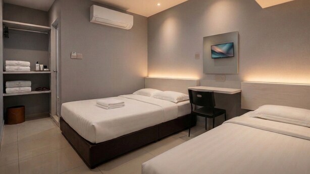 Ein modernes Hotelzimmer mit zwei Betten, einem Schreibtisch und einem Fernseher.