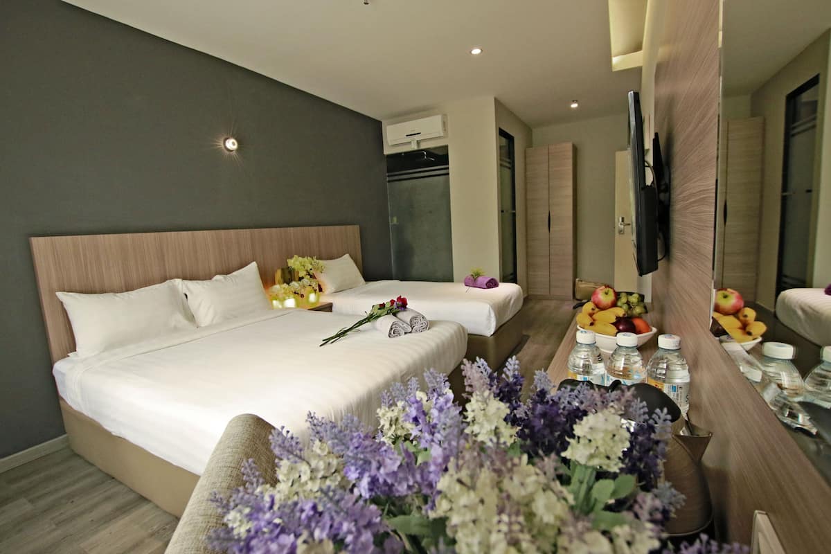 Een hotelkamer met een groot bed, een nachtkastje met fruit en flessen, en een spiegel.