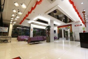 Un hall d’entrée moderne avec des sièges violets, un comptoir d’accueil et des décorations rouges.