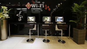 Zona de bar con un cartel de Wi-Fi gratuito, taburetes y una planta grande en maceta.