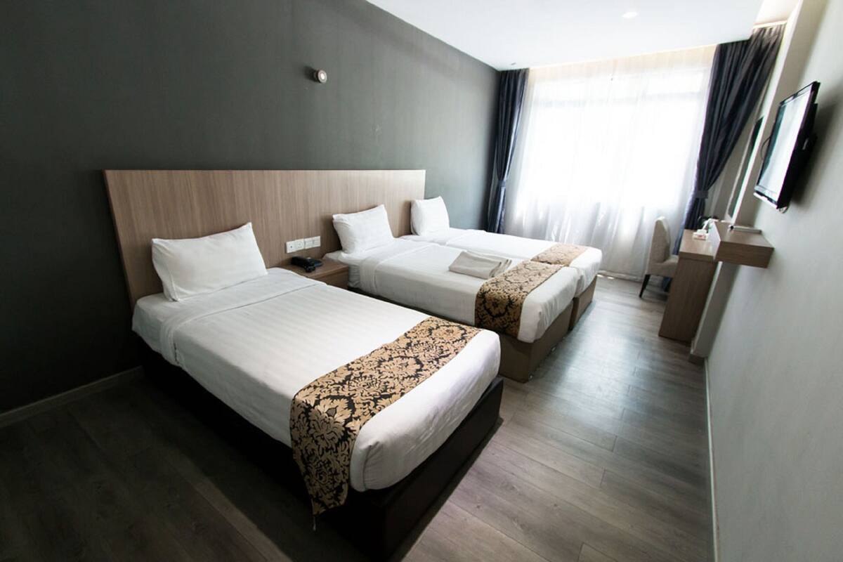 Een hotelkamer met twee bedden, een bureau en een televisie.